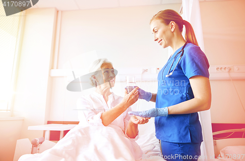 Image of nurse giving medicine to senior woman at hospital