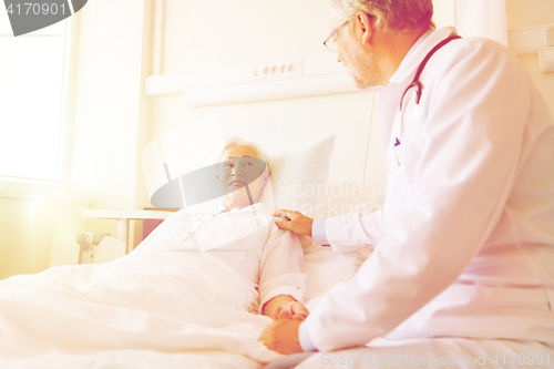 Image of doctor visiting senior woman at hospital ward