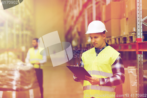 Image of man with clipboard in safety vest at warehouse