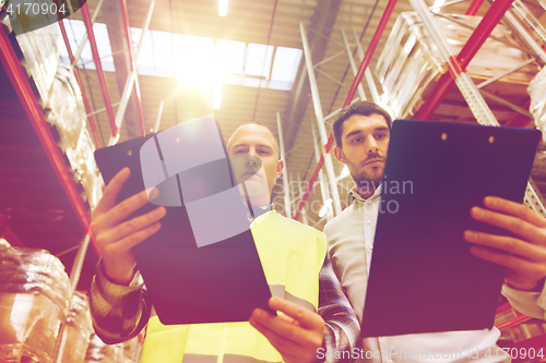 Image of worker and businessmen with clipboard at warehouse