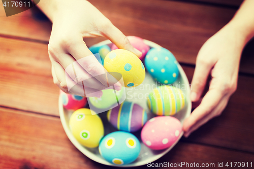 Image of close up of woman hands with colored easter eggs