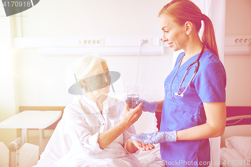 Image of nurse giving medicine to senior woman at hospital