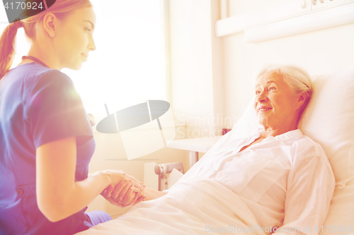 Image of doctor or nurse visiting senior woman at hospital