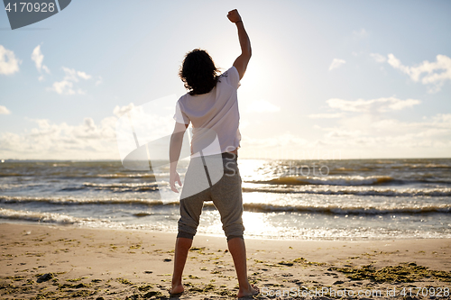 Image of man with rised fist on beach