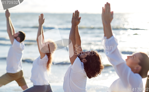 Image of group of people making yoga exercises on beach