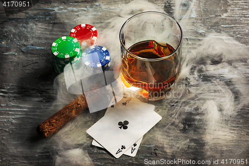 Image of Cigar, chips for gamblings, drink and playing cards