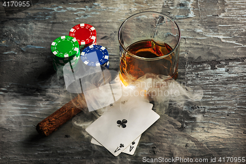 Image of Cigar, chips for gamblings, drink and playing cards