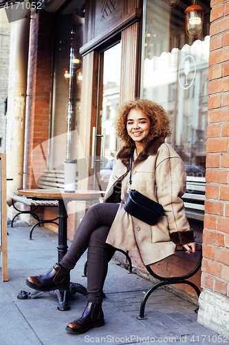 Image of young pretty african american women drinking coffee outside in c