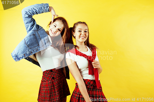 Image of lifestyle people concept: two pretty school girl having fun on yellow background, happy smiling students
