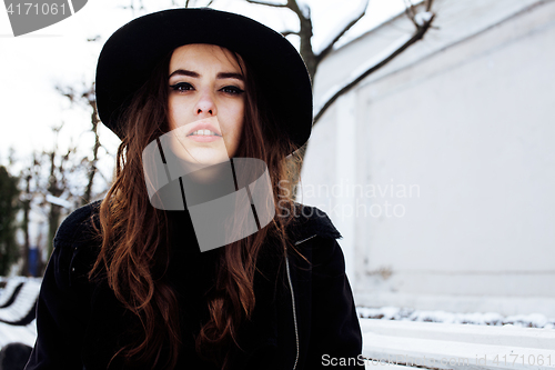 Image of young pretty modern hipster girl waiting on bench at winter snow park alone, lifestyle people concept