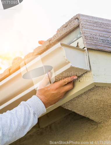 Image of Worker Attaching Aluminum Rain Gutter to Fascia of House.