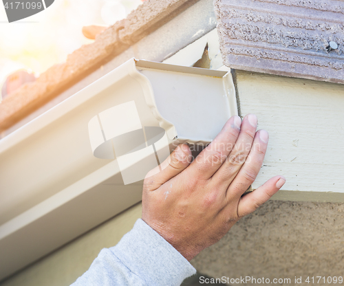 Image of Worker Attaching Aluminum Rain Gutter to Fascia of House.