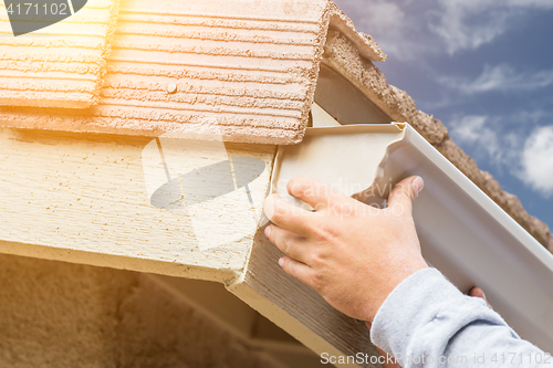 Image of Worker Attaching Aluminum Rain Gutter to Fascia of House.