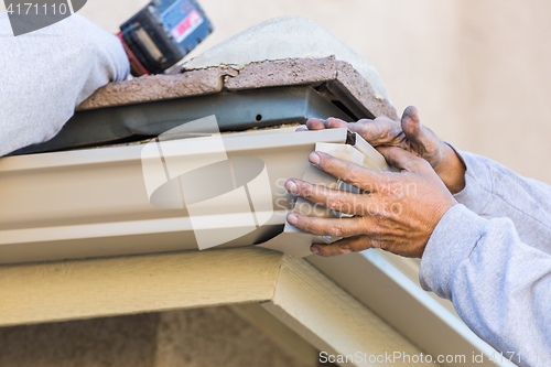 Image of Worker Attaching Aluminum Rain Gutter to Fascia of House.