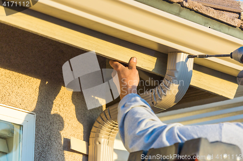 Image of Worker Attaching Aluminum Rain Gutter and Down Spout to Fascia o