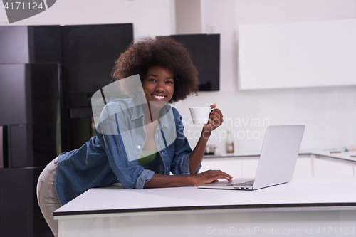 Image of smiling black woman in modern kitchen