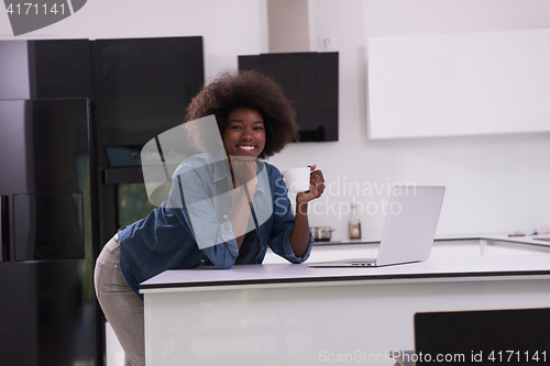 Image of smiling black woman in modern kitchen