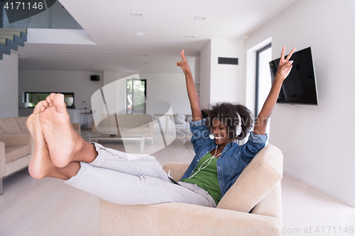 Image of African american woman at home in chair with tablet and head pho