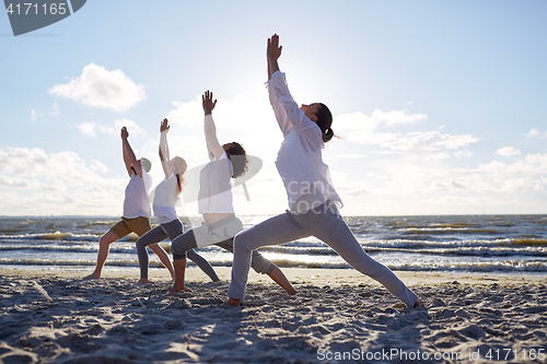 Image of group of people making yoga exercises on beach