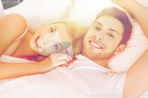 Image of happy couple lying in bed at home