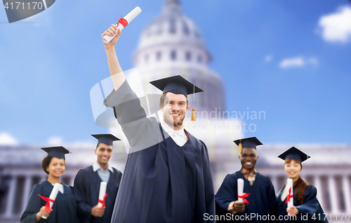 Image of happy students in mortar boards with diplomas