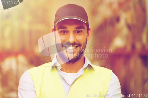 Image of happy man in reflective safety vest at warehouse