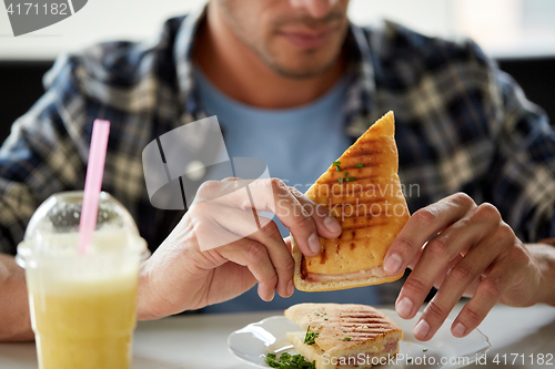 Image of close up of man eating sandwich at cafe for lunch