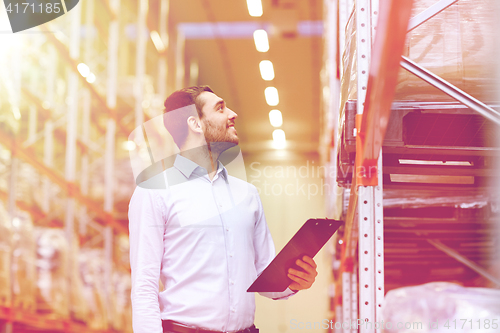 Image of happy businessman with clipboard at warehouse