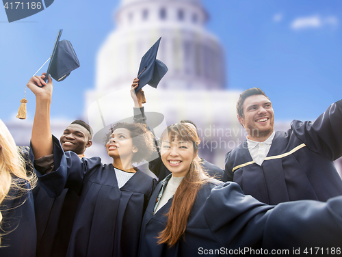 Image of happy students or bachelors waving mortar boards