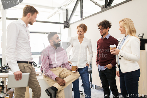 Image of happy business team drinking coffee at office