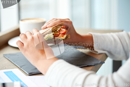 Image of woman eating salmon panini sandwich at restaurant