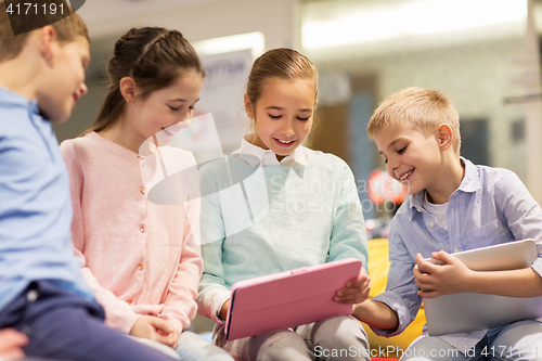 Image of group of happy children with tablet pc at school