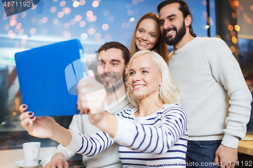 Image of happy friends with tablet pc taking selfie at cafe