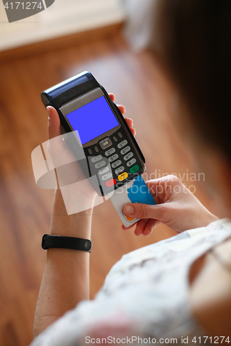 Image of Hand putting plastic card into credit card terminal