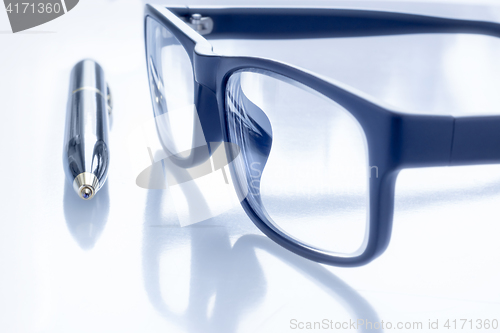 Image of Black eye glasses and ballpoint pen