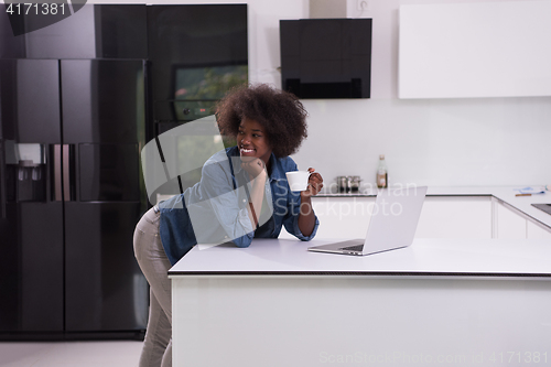 Image of smiling black woman in modern kitchen