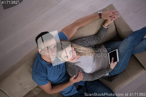 Image of youg couple in living room with tablet top view