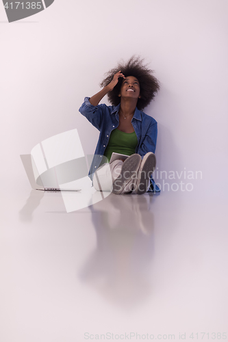 Image of african american woman sitting on floor with laptop