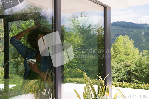 Image of African American woman drinking coffee looking out the window