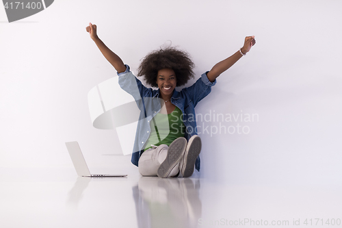 Image of african american woman sitting on floor with laptop