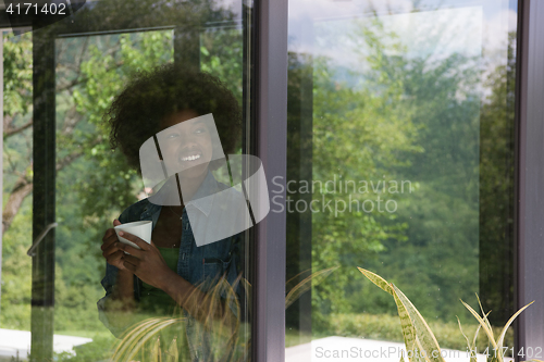 Image of African American woman drinking coffee looking out the window