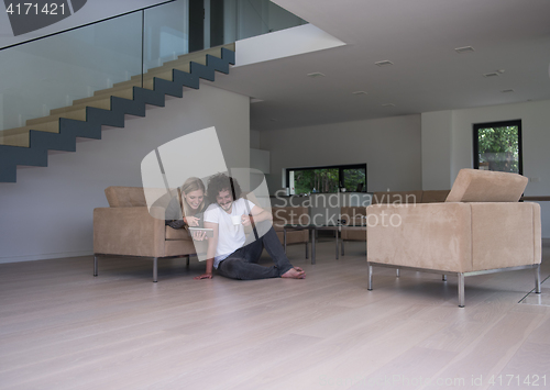 Image of couple relaxing at  home with tablet computers