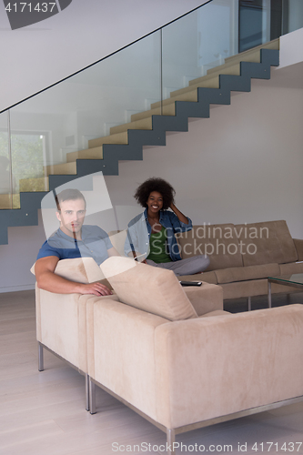 Image of multiethnic couple relaxing at  home with tablet computers