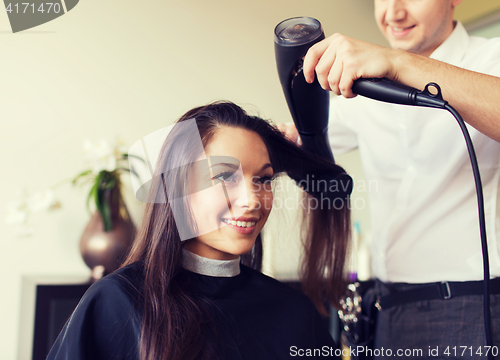 Image of happy woman with stylist making hairdo at salon