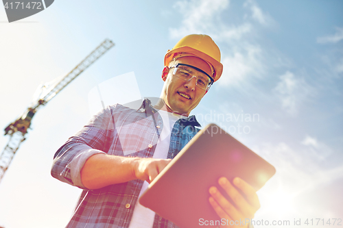 Image of builder in hardhat with tablet pc at construction