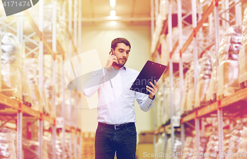 Image of man with clipboard and smartphone at warehouse