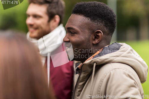 Image of happy friends walking along autumn park
