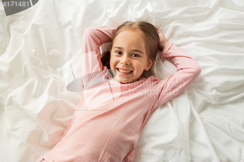 Image of happy little girl lying in bed at home