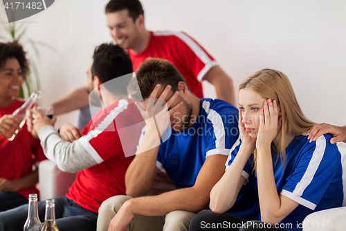 Image of friends or football fans watching soccer at home