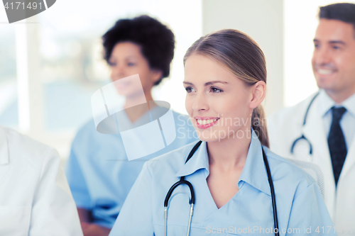 Image of happy doctor over group of medics at hospital